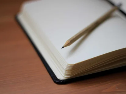 A pencil lying on top of a blank notebook